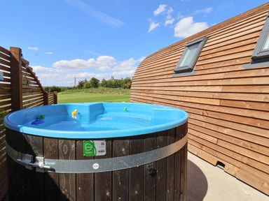 An outdoor hot tub with rubber ducks next to a wooden building at Parliament in Little Kelk near Bridlington