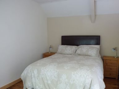 A bedroom with a double bed and two wooden nightstands at Spring Garden Cottage in Laugharne