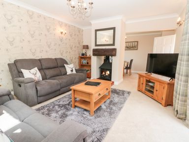 A living room with two grey sofas a wooden coffee table and a fireplace at Church View in Withernwick near Aldbrough