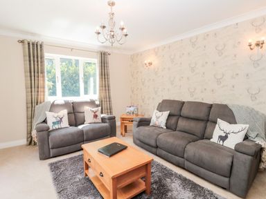 A living room with two gray sofas a wooden coffee table and a window with curtains at Church View in Withernwick near Aldbrough