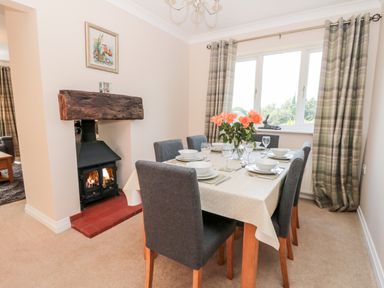 A dining room with a table set for six people and a lit fireplace at Church View in Withernwick near Aldbrough