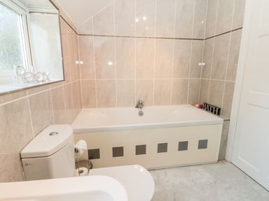 A bathroom with a bathtub toilet and window at Church View in Withernwick near Aldbrough