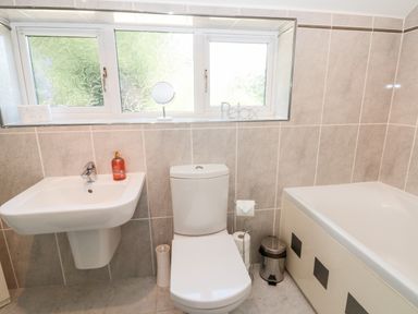 A bathroom with a sink, toilet, bathtub, window with frosted glass and bathroom accessories at Church View in Withernwick near Aldbrough