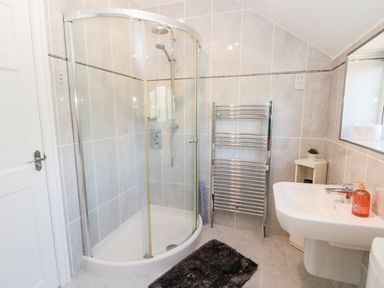 A bathroom with a corner shower enclosure a sink and a towel rack at Church View in Withernwick near Aldbrough