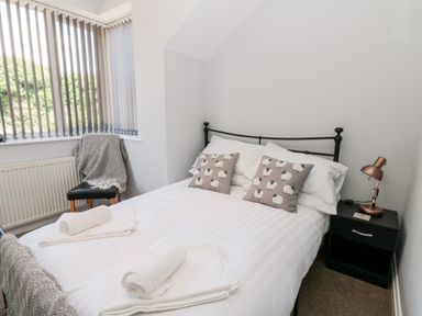 A bedroom with a bed with sheep patterned pillows and a bedside table with a lamp at Church View in Withernwick near Aldbrough