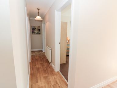 A hallway with wooden flooring a radiator and a hanging light at Church View in Withernwick near Aldbrough