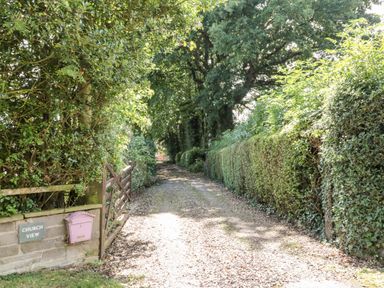 A gravel driveway lined with hedges and trees at Church View in Withernwick near Aldbrough
