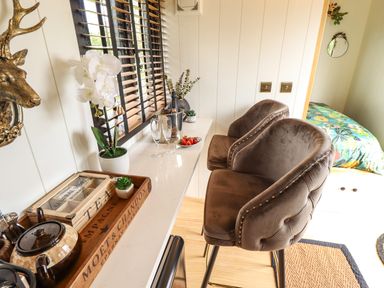 A kitchen counter with two brown bar stools and a tray with teapot and tea boxes at Portland Luxury Glamping in Nottingham