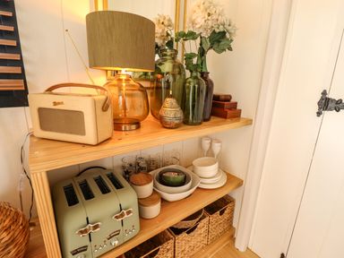 A wooden shelf with a lamp radio vases and kitchenware at Portland Luxury Glamping Nottingham