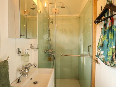 A bathroom with a sink a mirror a glass shower enclosure and a floral bag hanging on the wall at Portland Luxury Glamping in Nottingham