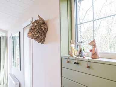 A decorative animal head on a wall and three small animal figurines on a windowsill at Fern Lodge in Allithwaite near Cartmel