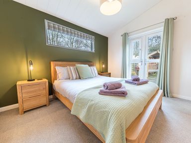 A bedroom with a double bed and wooden bedside tables at Fern Lodge in Allithwaite near Cartmel