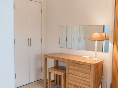 A wooden dressing table with a stool and a lamp next to a white double door at Fern Lodge in Allithwaite near Cartmel