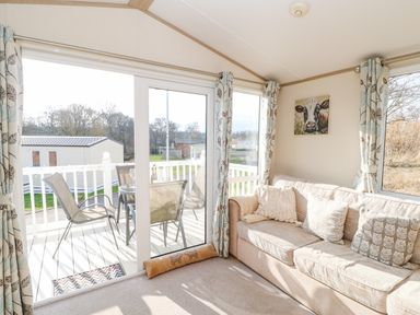 A living room with beige sofa and cushions next to glass sliding door opening to patio with table and chairs at 46 Willowburn in Felton