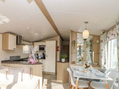 A kitchen and dining area with table set for four and a sofa in a home at 46 Willowburn in Felton