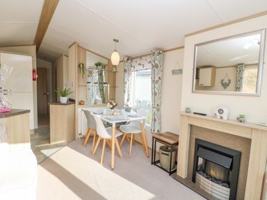 A dining area with a table and four chairs next to a fireplace with a mirror above at 46 Willowburn in Felton