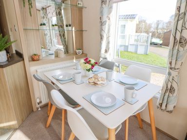 A dining area with a white table set for four with plates mugs and a vase of flowers at 46 Willowburn in Felton