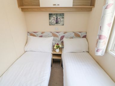 A bedroom with two single beds separated by a small wooden nightstand with flowers 46 Willowburn Felton