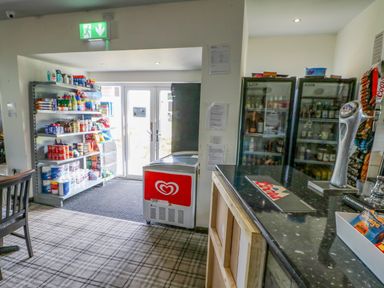 Interior view of a small shop with shelves stocked with groceries and household items near double glass doors at 46 Willowburn in Felton