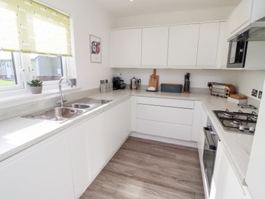A kitchen with a sink, stove, and cabinets at The Beach House (Beadnell) Beadnell