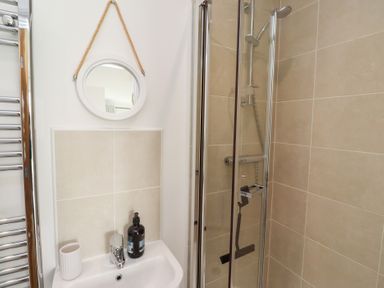 A bathroom featuring a shower, mirror, and sink at The Beach House (Beadnell)
