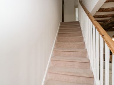 Carpeted staircase with white railing and wooden handrail leading to an upper floor at High Cogges Farm Holiday Cottages in Witney