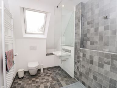 A bathroom with a toilet sink towel radiator and shower area at High Cogges Farm Holiday Cottages Witney