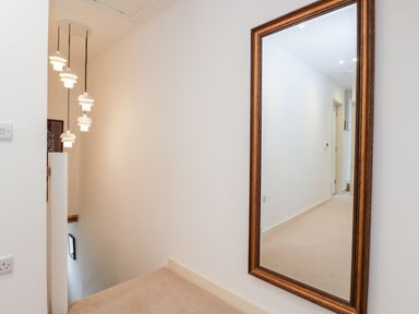 A hallway with a large wall mirror and hanging pendant lights at High Cogges Farm Holiday Cottages in Witney