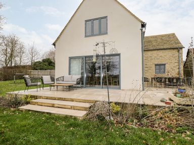 Outdoor patio area with seating and table outside a house at High Cogges Farm Holiday Cottages Witney