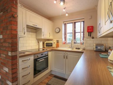 A kitchen with wooden countertops white cabinets an oven a microwave a sink and a window at 10 Ruston Reaches in East Ruston near Stalham