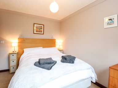 A bedroom with a double bed two bedside tables with lamps and framed pictures on the wall at 10 Ruston Reaches East Ruston near Stalham