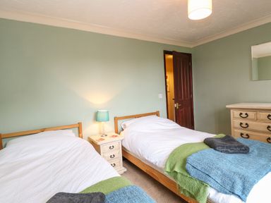 A bedroom with two single beds bedside table with lamp and chest of drawers at 10 Ruston Reaches in East Ruston near Stalham