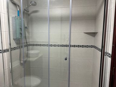 A shower enclosure with sliding glass doors a wall-mounted showerhead and a tiled wall with a decorative border at 10 Ruston Reaches East Ruston near Stalham