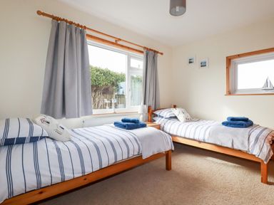 A bedroom with two single beds with striped bedding and blue towels on them at Brookfield in St Gennys near Wainhouse Corner