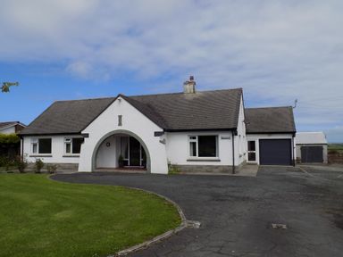 A single-story house with a curved driveway lawn and garage at Brookfield in St Gennys near Wainhouse Corner