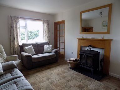 A living room with sofas a fireplace with wood burner and mirror above at Brookfield in St Gennys near Wainhouse Corner
