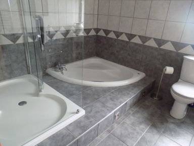 A bathroom with a corner bathtub a shower cubicle and a toilet at Brookfield in St Gennys near Wainhouse Corner
