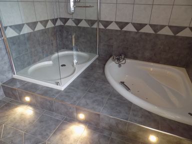 A bathroom with a tiled floor a raised platform with a shower enclosure and a bathtub at Brookfield in St Gennys near Wainhouse Corner