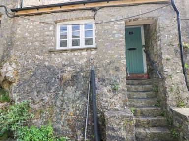 Front door with number 10 accessed by stone steps and a window on stone exterior wall at 10 Westgate Hill in Pembroke