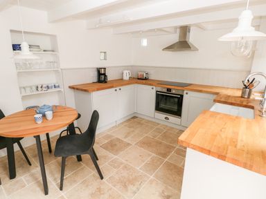 A kitchen with wooden countertops a round wooden table with black chairs shelves with dishes at 10 Westgate Hill in Pembroke