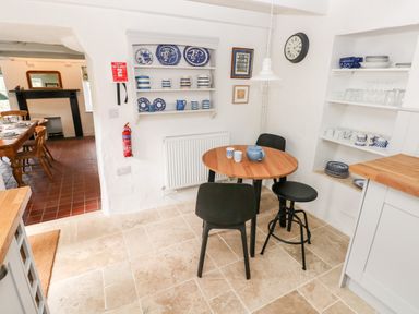 A kitchen corner with a round wooden table and three black chairs next to shelves holding blue and white dishes at 10 Westgate Hill in Pembroke