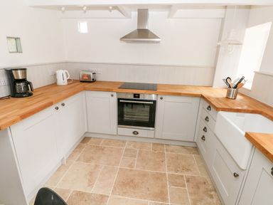 A kitchen with wooden countertops white cabinets a coffee maker kettle toaster oven stovetop and kitchen utensils at 10 Westgate Hill in Pembroke