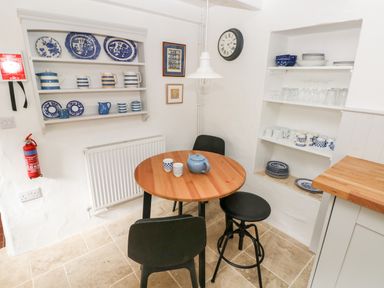 A kitchen corner with a round wooden table, black chairs, shelves with blue and white dishes and mugs on the wall at 10 Westgate Hill in Pembroke