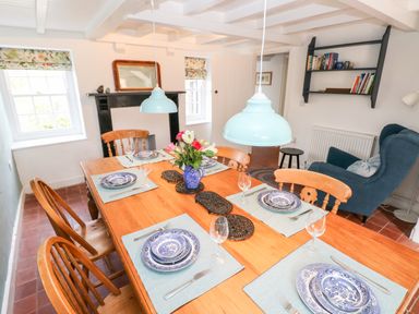 A dining area with a wooden table set with blue and white plates and floral centerpiece at 10 Westgate Hill in Pembroke