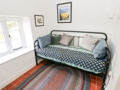 A small room with a metal-frame daybed with cushions a window and two framed pictures on the walls at 10 Westgate Hill in Pembroke