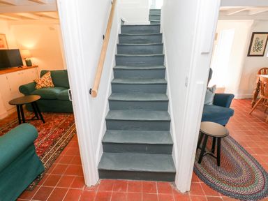 A staircase with painted wooden steps between two rooms with sofas and side tables at 10 Westgate Hill in Pembroke