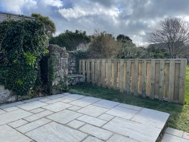 A stone patio with a wooden fence and stone wall covered in ivy at 10 Westgate Hill in Pembroke