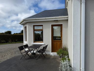 An outdoor area with a table and chairs in front of a door at Geesala