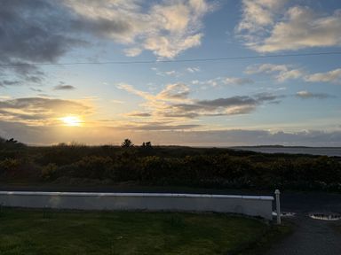 A sunset over the sea with grass and bushes at Geesala