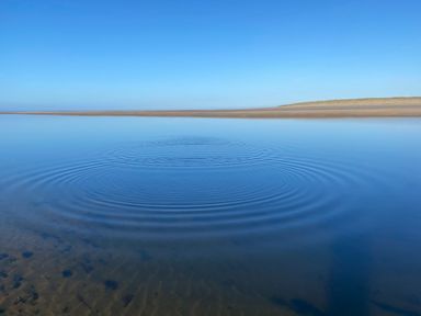 A body of water with ripples and blue sky at Geesala
